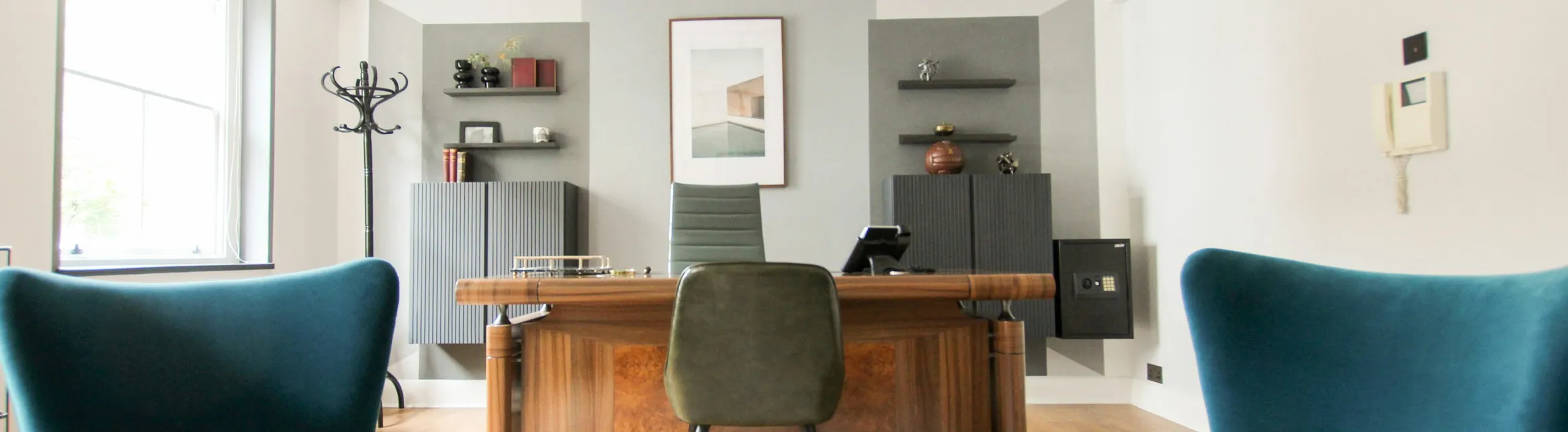 A bright consulting room with two armchairs and a desk by the window