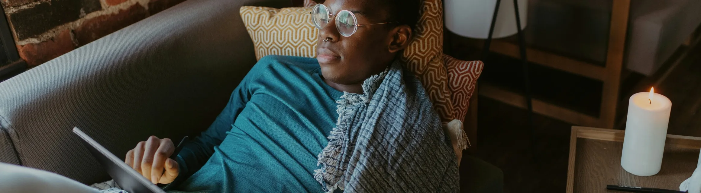 A man sitting quietly with a tablet in a calm, softly lit room