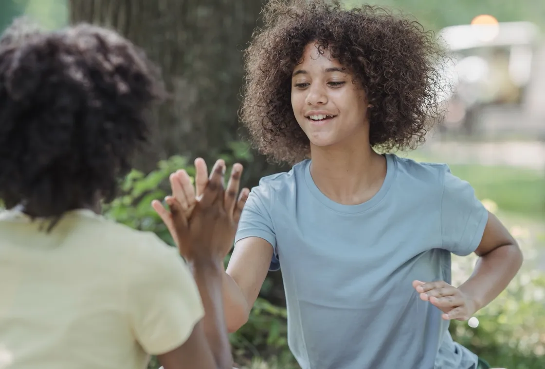 Deux enfants jouant à un jeu de mains sur une couverture dans un parc