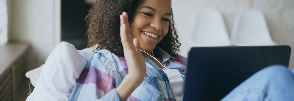 Une femme chez elle, sur son canapé, en séance avec un clinicien par visioconférence