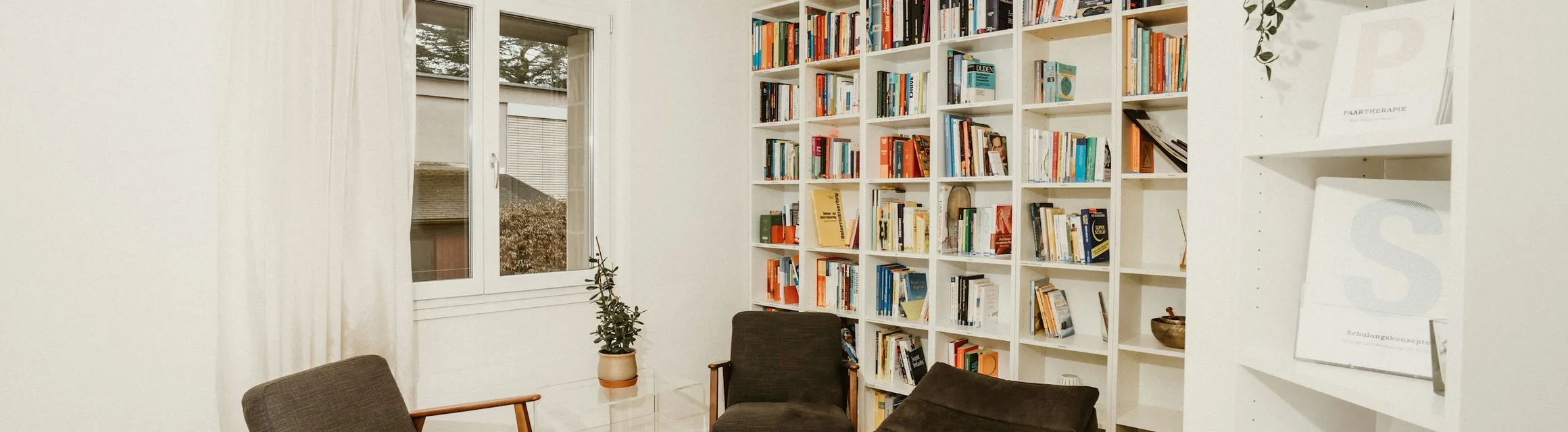 A quiet room with an armchair, a chaise longue and full bookshelves