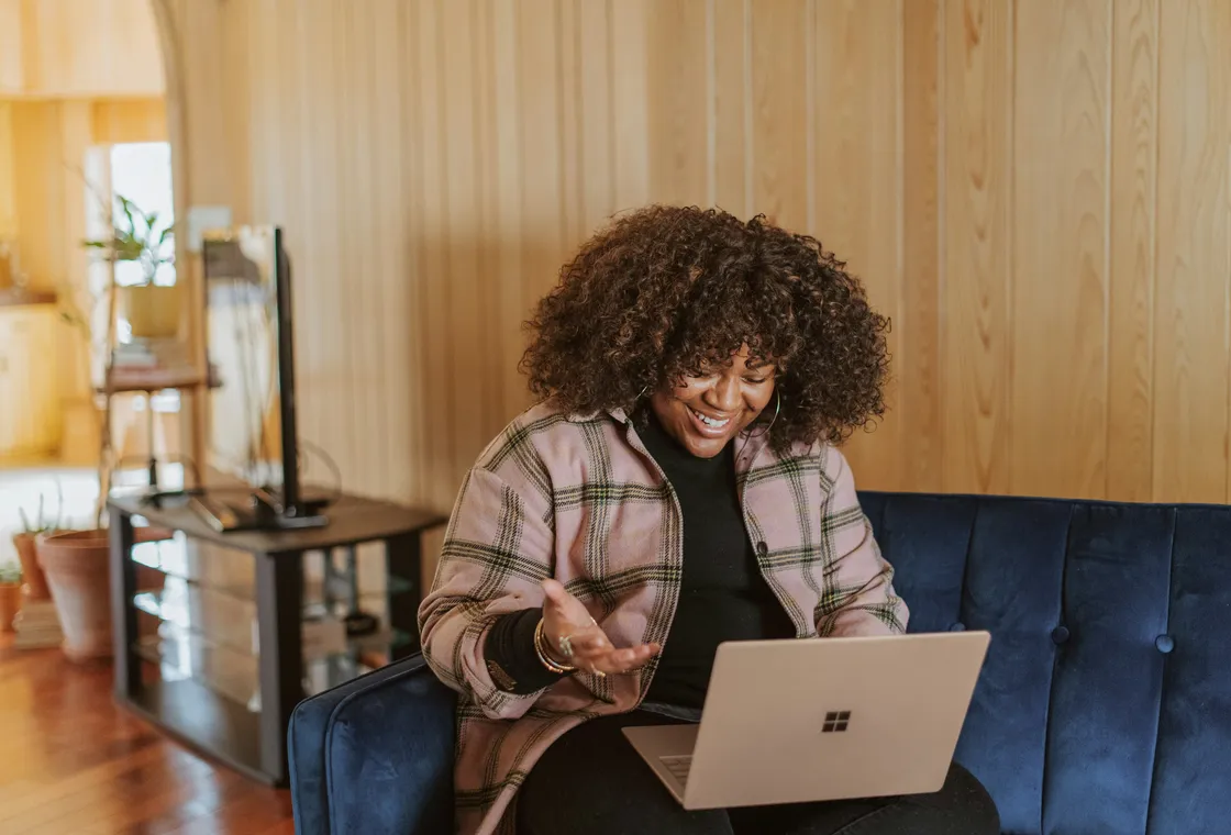 A woman in a warm wood-panelled room, talking during an online session